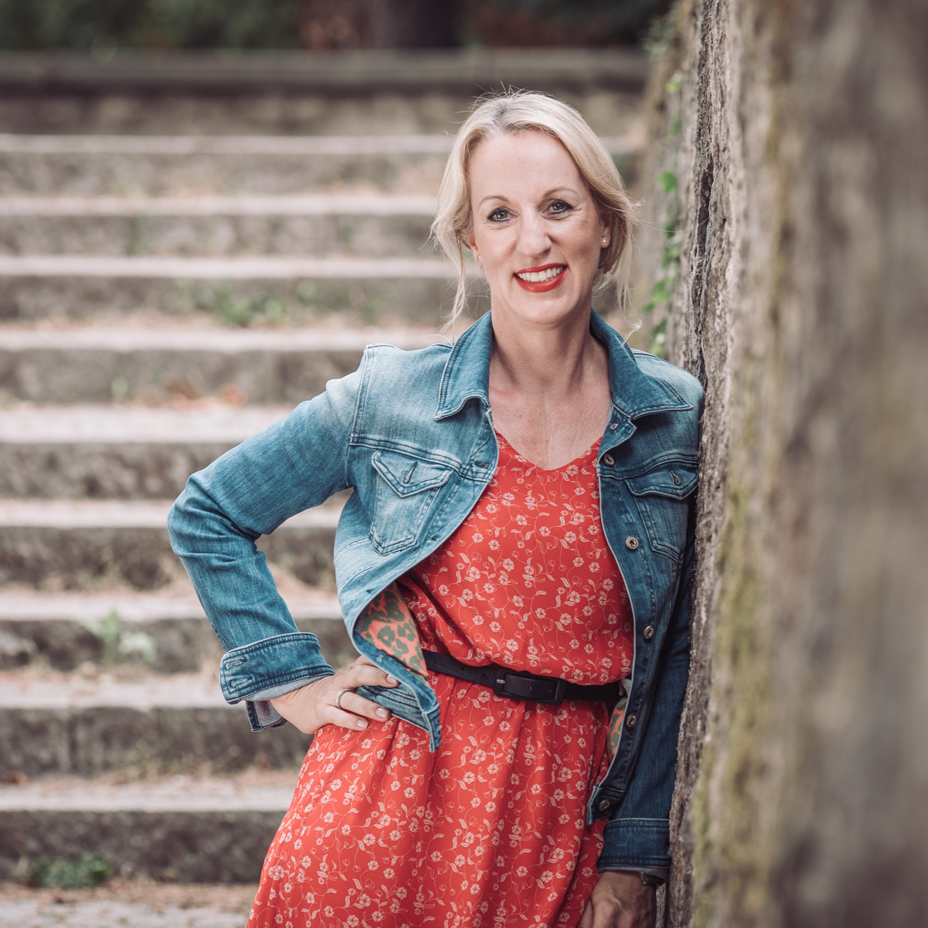 Yvonne lehnt an Mauer und lacht